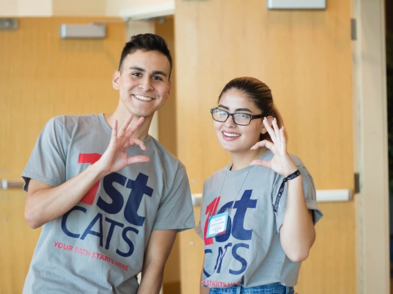 Two U of A students wearing first cats t-shirts and throwing the wildcat sign.