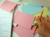 Image of a desk with a notebook and flashcards.  Hand at bottom right with a pencil between thumb and middle finger.